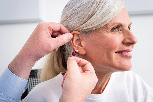 Ältere Frau bekommt ein modernes Hörgerät eingesetzt, Hörhilfe bei Hörverlust.